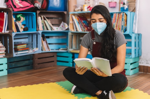 Jeune enseignant mexicain lisant un livre sur une salle de classe vide