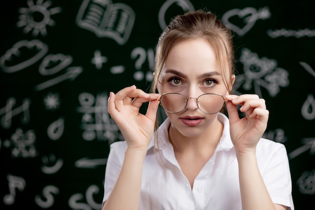 Jeune enseignant se tient près du tableau noir dans la salle de classe