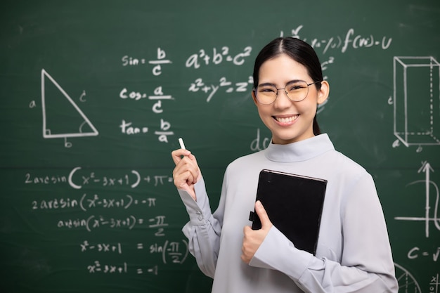 Jeune enseignante asiatique enseignant tenant un livre et une visioconférence à la craie avec une étudiante regardant la caméra