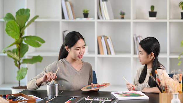 Jeune enseignante asiatique prenant soin des enfants tout en peignant des images dans un cours de peinture