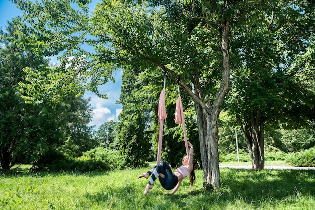 Un jeune entraîneur de yoga formé de manière athlétique s'entraîne à l'extérieur sous un arbre