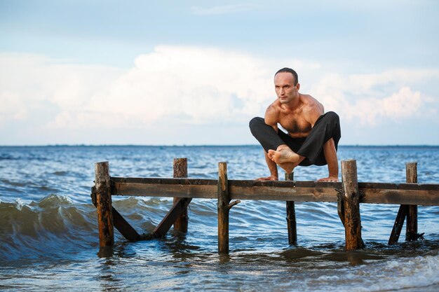 Jeune entraîneur de yoga pratiquant des exercices de yoga sur une jetée en bois au bord d'une mer ou d'une rivière