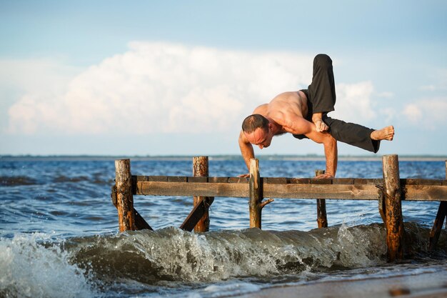 Jeune entraîneur de yoga pratiquant le yoga dandasana pose sur une jetée en bois au bord d'une mer ou d'une rivière