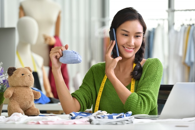 Jeune entrepreneur asiatique / créatrice de mode pour vêtements de bébé travaillant en studio