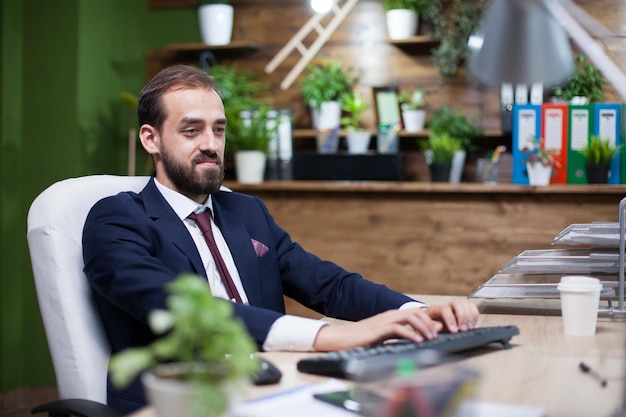 Jeune entrepreneur confiant travaillant sur son ordinateur vêtu d'un costume d'affaires. Bel homme d'affaires.