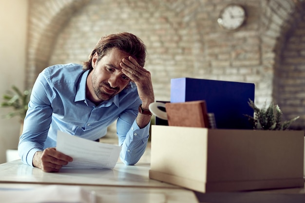 Jeune entrepreneur déçu lisant un avis après avoir regardé son travail au bureau