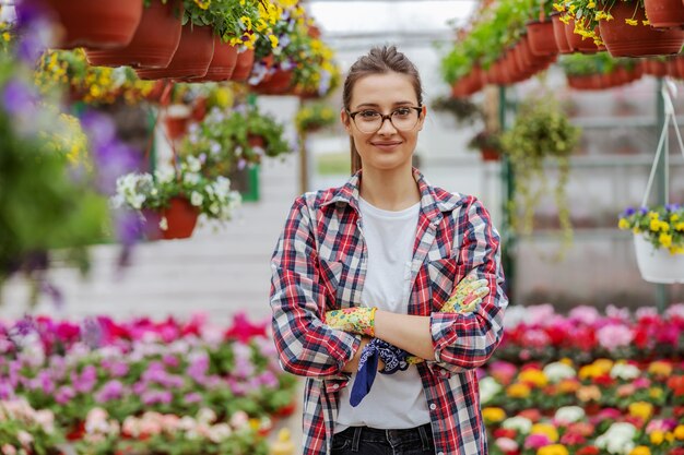 Jeune entrepreneur femme souriante debout dans la serre avec les bras croisés et regardant la caméra.