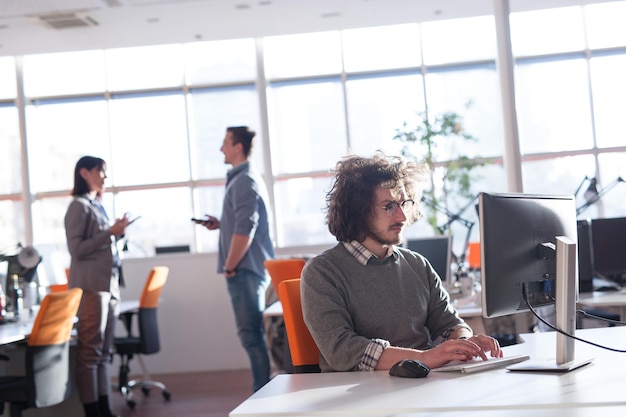 Jeune entrepreneur indépendant travaillant à l'aide d'un ordinateur dans un espace de coworking