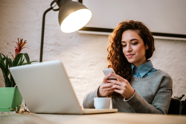 Jeune entrepreneur sur son lieu de travail à l&#39;aide d&#39;un ordinateur portable et d&#39;un téléphone.