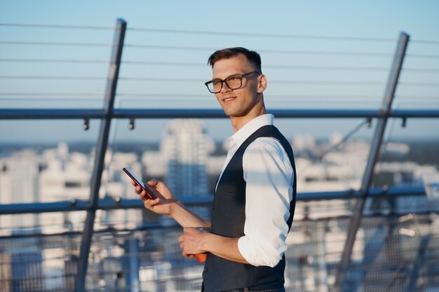 Jeune entrepreneur souriant avec un smartphone regardant le venu