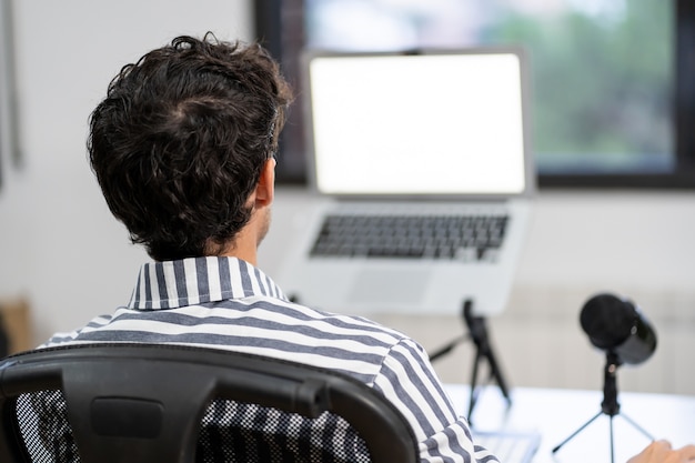 Jeune entrepreneur travaille à domicile dans son bureau avec l'ordinateur devant une fenêtre