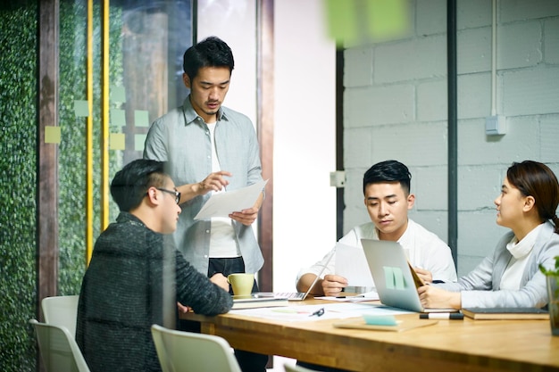 Photo une jeune équipe d'affaires asiatique se réunit au bureau.