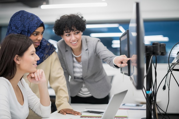 jeune équipe commerciale multiethnique de développeurs de logiciels travaillant ensemble à l'aide d'un ordinateur portable tout en écrivant du code de programmation dans un bureau de démarrage moderne