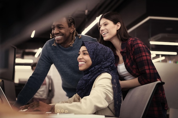 jeune équipe commerciale multiethnique de développeurs de logiciels travaillant ensemble à l'aide d'un ordinateur portable tout en écrivant du code de programmation dans un bureau de démarrage moderne