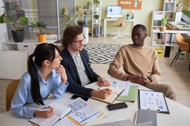 Une jeune équipe d'entrepreneurs assise à la table de réunion dans le bureau et faisant du brainstorming