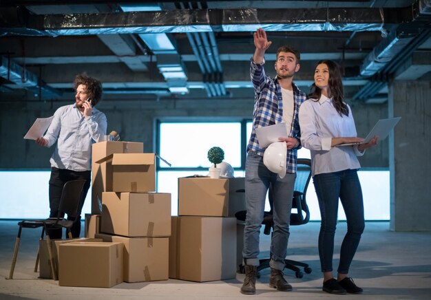 jeune équipe de gens d'affaires en groupe, architecte et ingénieur sur le chantier de construction vérifiant les documents et le flux de travail d'entreprise à l'aide d'un ordinateur portable dans le nouveau bureau de démarrage