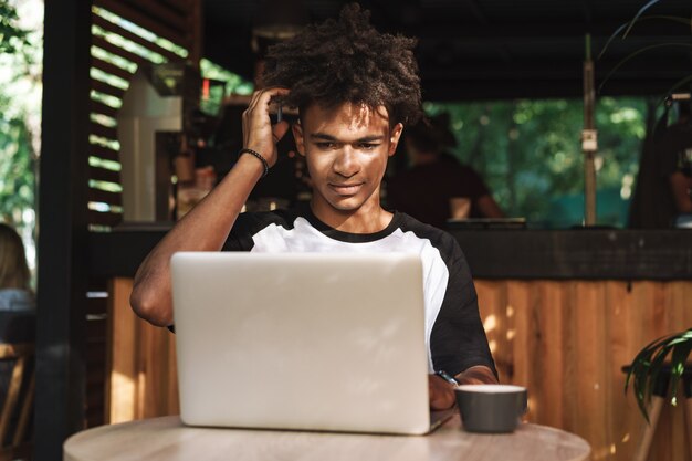 Jeune étudiant africain d'adolescent s'asseyant au café