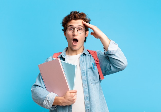 Jeune étudiant à l'air heureux, étonné et surpris, souriant et réalisant de bonnes nouvelles incroyables et incroyables