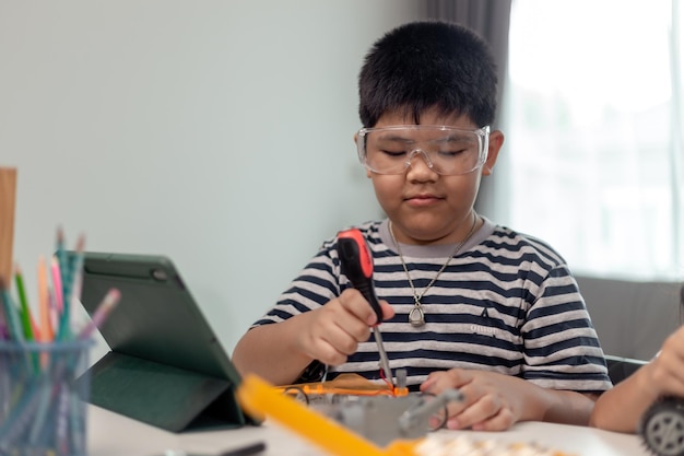 Un jeune étudiant asiatique apprend à distance en ligne à la maison à coder des voitures robotiques et des câbles électroniques en STEM STEAM mathématiques ingénieur science technologie code informatique en robotique pour les enfants