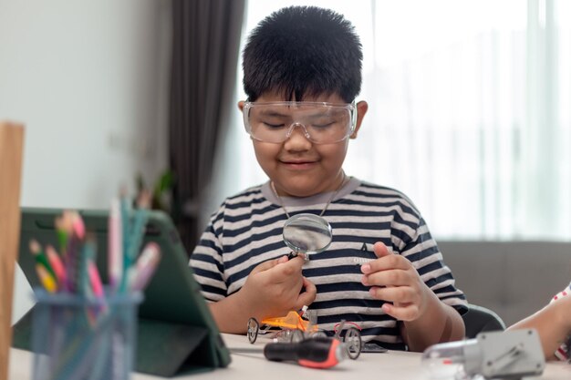 Un jeune étudiant asiatique apprend à distance en ligne à la maison à coder des voitures robotiques et des câbles électroniques en STEM STEAM mathématiques ingénieur science technologie code informatique en robotique pour les enfants