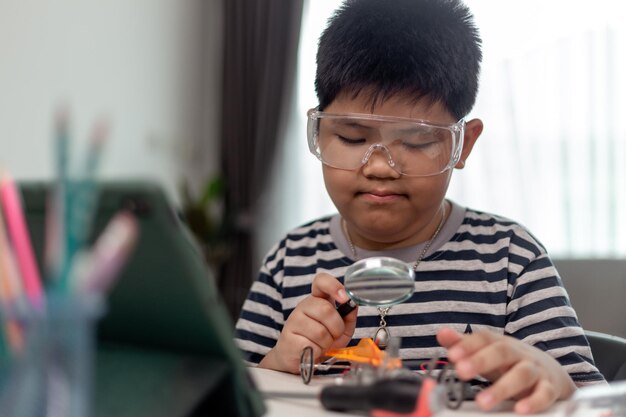 Un jeune étudiant asiatique apprend à distance en ligne à la maison à coder des voitures robotiques et des câbles électroniques en STEM STEAM mathématiques ingénieur science technologie code informatique en robotique pour les enfants