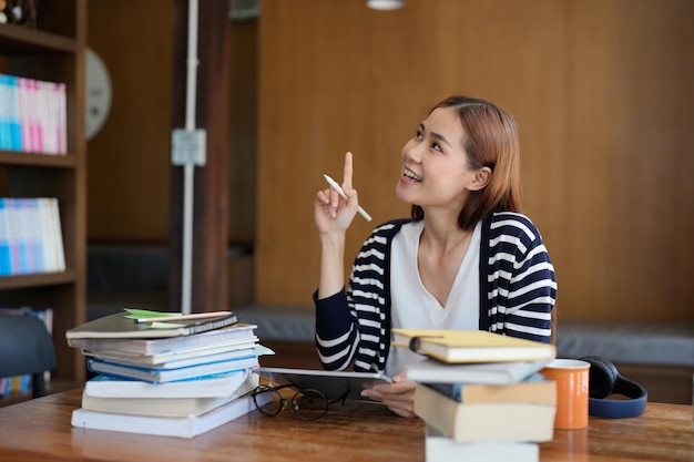 Jeune étudiant asiatique intelligent ayant une idée de démarrage en lisant un livre