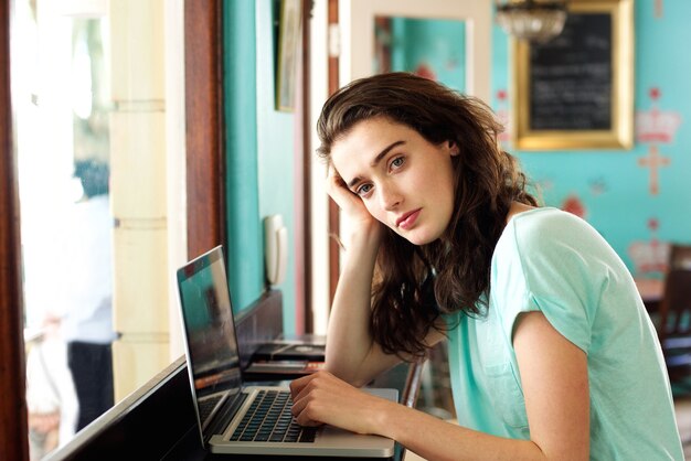 jeune étudiant assis au café avec un ordinateur portable