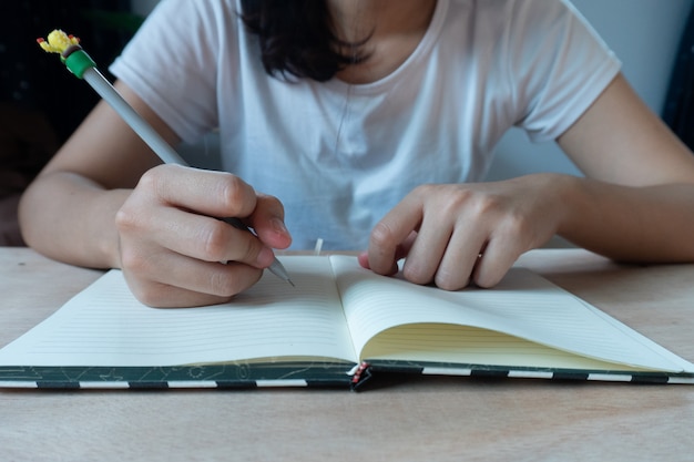 Jeune étudiant assis à table et prendre des notes dans le cahier