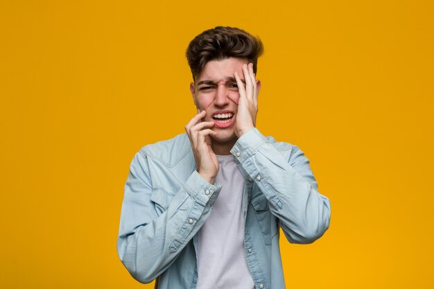 Jeune étudiant beau vêtu d'une chemise en jean pleurnichant et pleurant de façon inconsolable.