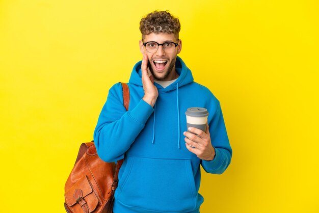 Jeune étudiant blond isolé sur fond jaune avec une expression faciale surprise et choquée