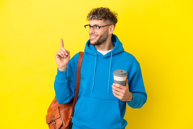 Jeune étudiant blond isolé sur fond jaune pointant vers le haut une excellente idée