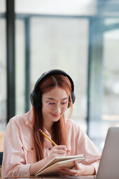 Un jeune étudiant en collage qui utilise un ordinateur et un appareil mobile pour étudier en ligne