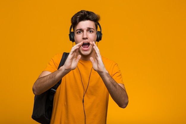 Jeune étudiant cool homme écoutant de la musique avec des écouteurs souriant joyeusement pointant avec l'index loin.