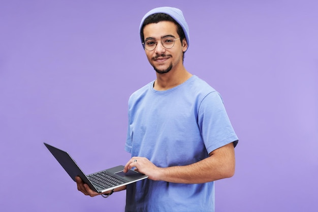 Jeune étudiant ou designer réussi tenant un ordinateur portable tout en regardant la caméra