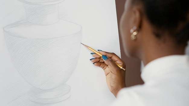 Jeune étudiant dessinant un vase sur une toile blanche et un chevalet en classe d'art. Femme créative utilisant un crayon pour dessiner des croquis sur papier et développer des compétences artistiques pour la croissance. Fermer. Prise de vue à main levée