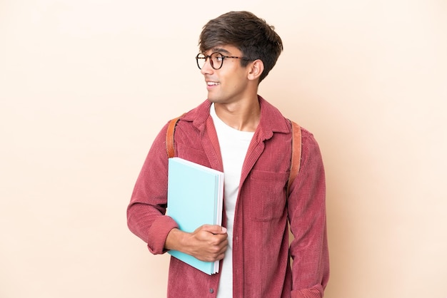 Jeune étudiant homme de race blanche isolé sur fond ocre à côté