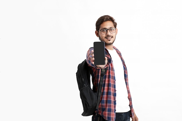 Jeune étudiant indien montrant l'écran du smartphone sur un mur blanc