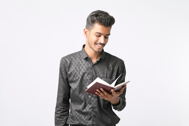 Jeune étudiant indien tenant le journal à la main sur fond blanc.