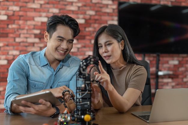 Jeune étudiant ingénieur masculin et féminin apprenant la programmation pour contrôler le robot bras doigt