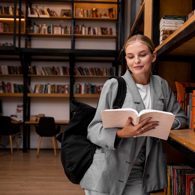 Photo jeune étudiant lisant à la bibliothèque