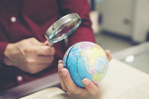 Jeune étudiant lisant un livre et tenant un modèle de la terre à la main