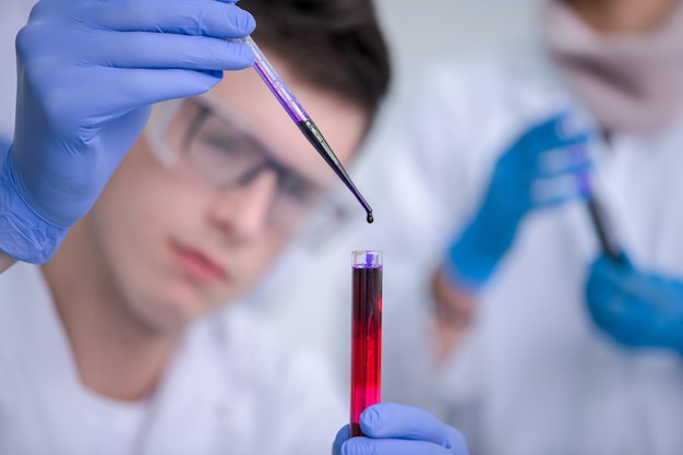 jeune étudiant avec des lunettes de protection faisant une expérience de chimie dans un concept de laboratoire, d'éducation et de médecine lumineux