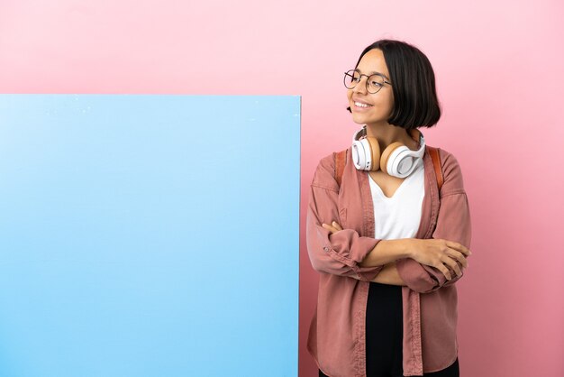 Jeune étudiant métisse femme avec une grande bannière sur fond isolé à la recherche sur le côté