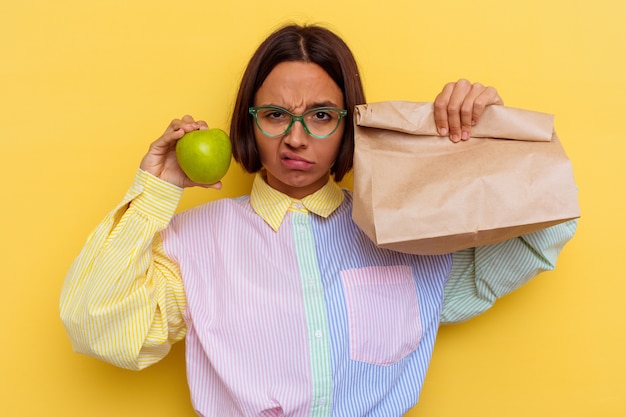 Photo jeune étudiant métisse femme prenant le déjeuner isolé sur mur jaune