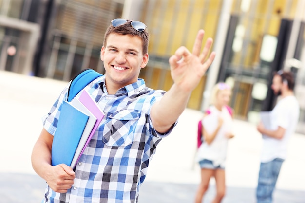 un jeune étudiant montrant un signe ok sur le campus