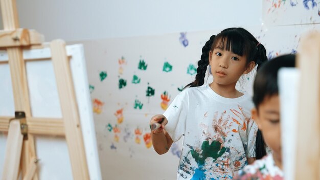 Jeune étudiant peint ou dessine une toile sur un mur taché en cours d'art Érudition