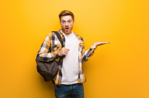 Jeune étudiant Rousse Homme Tenant Quelque Chose Sur La Main De Paume