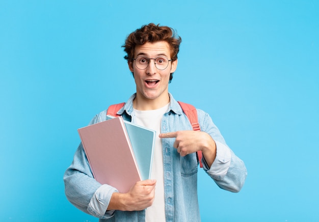 Jeune étudiant se sentant heureux, surpris et fier, se montrant lui-même avec un regard excité et étonné