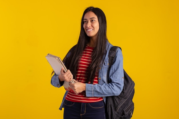 Jeune étudiant tenant un sac à dos et des livres en studio photo