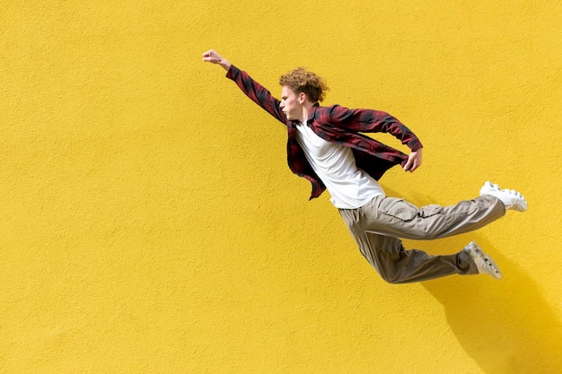 un jeune étudiant vole rapidement vers l'avant dans les airs sur fond de mur jaune isolé